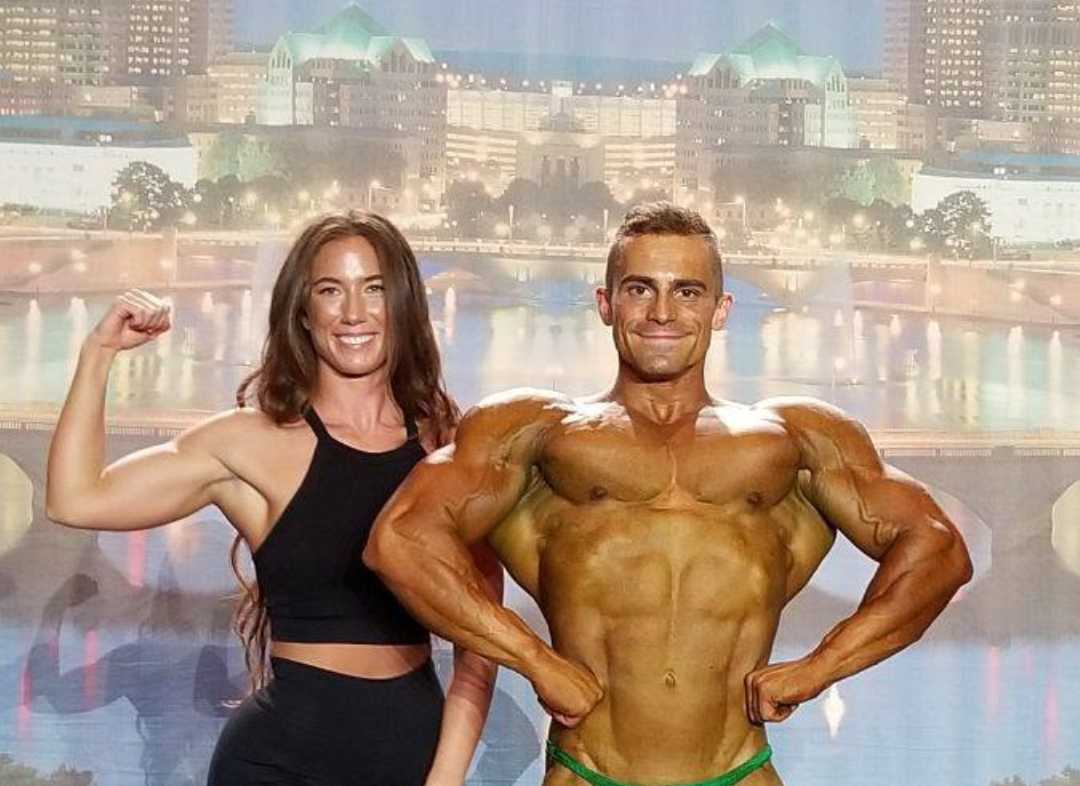 Jacob and Symone Chandler pose on stage after a big win for Jacob to move on to professional bodybuilding competitions.
