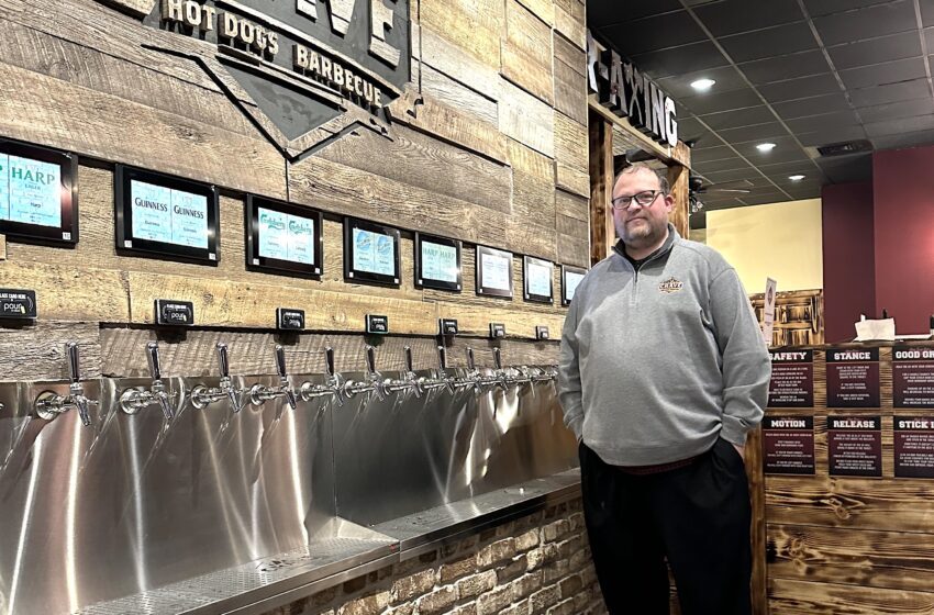 Crave co owner Brad Fuchs stands next to the restaurants unique self pour beer wall