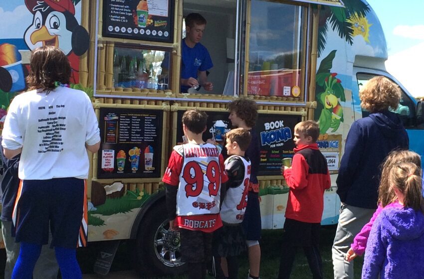 A line of customers forms alongside the Kona Ice truck.
